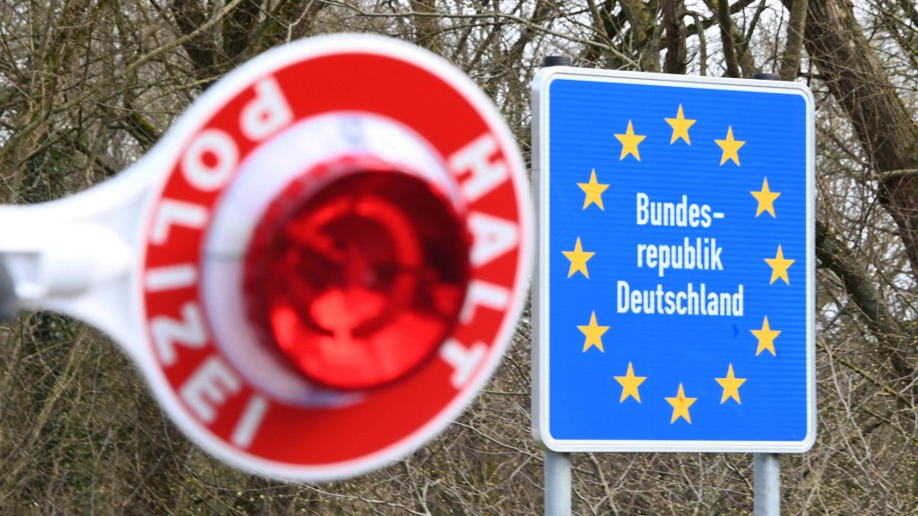 Rote Polizeikelle vor einem Grenzschild zu Deutschland