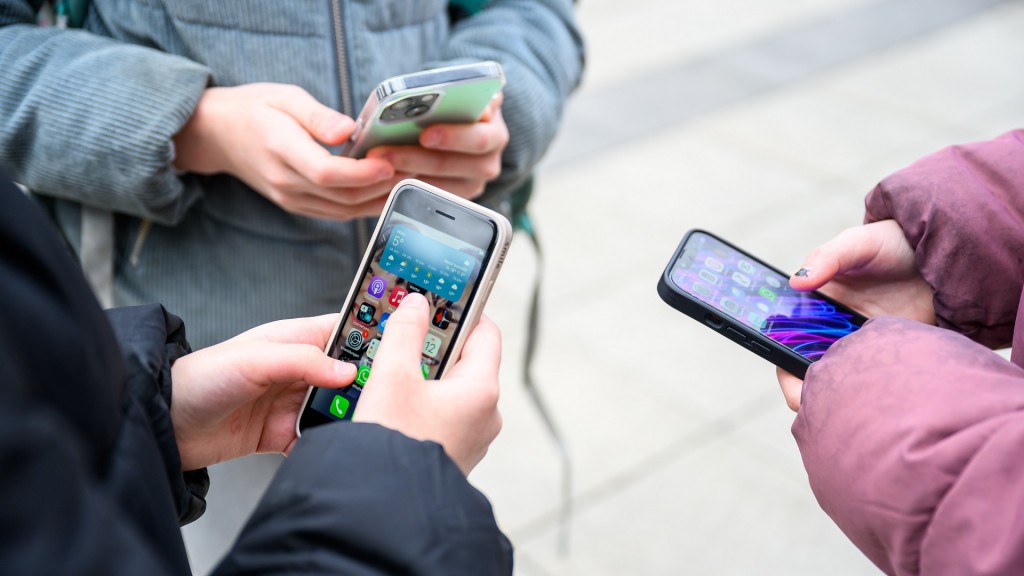 Schüler stehen mit Smartphones in der Hand auf dem Schulhof