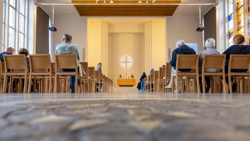 Besucher sitzen vor dem Gedenkgottesdienst in einer evangelischen Kirche