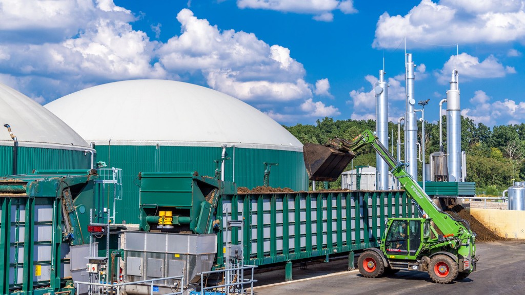 Ein Radlader kippt Biomasse in eine Biogasanlage