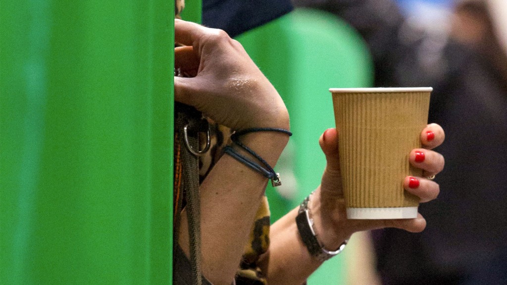 Eine Frau hält einen Getränkebecher aus Pappe in der Hand