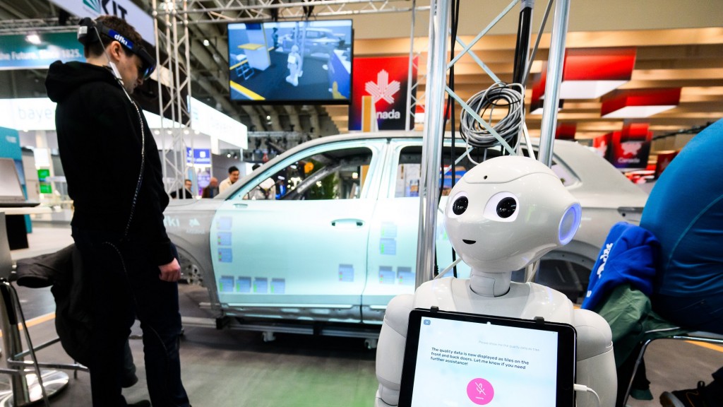 Ein Mitarbeiter steht bei der Industriemesse Hannover Messe 2025 am Stand vom dfki - Deutsches Forschungszentrum für Künstliche Intelligenz vor der Karosserie eines VW Tiguan, auf dem mit künstlicher Intelligenz Daten projiziert werden. Ein Roboter die