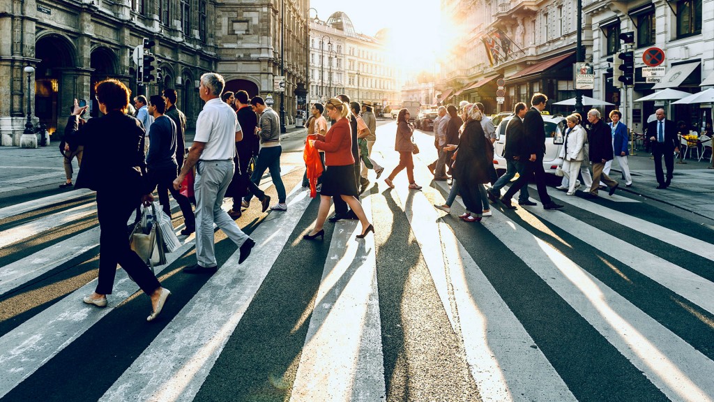 Menschen gehen über eine Straße im Gegenlicht der Sonne
