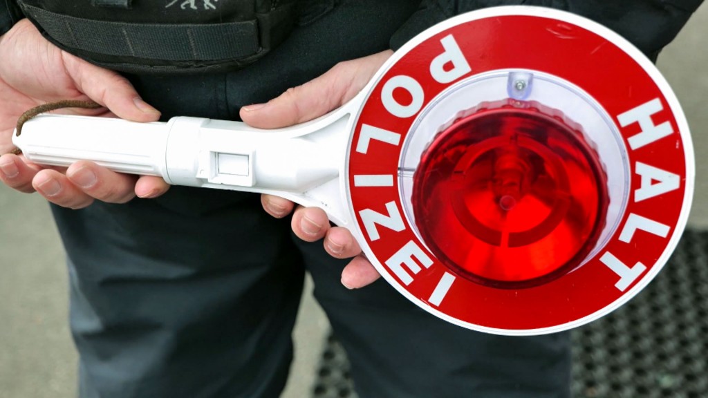 Ein Polizist hält eine Verkehrskelle in den Händen