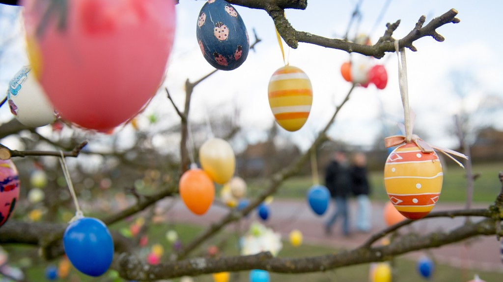Bunte Ostereier hängen an einem Baum. Regen und Kälte bestimmen das Wetter an den Osterfeiertagen.