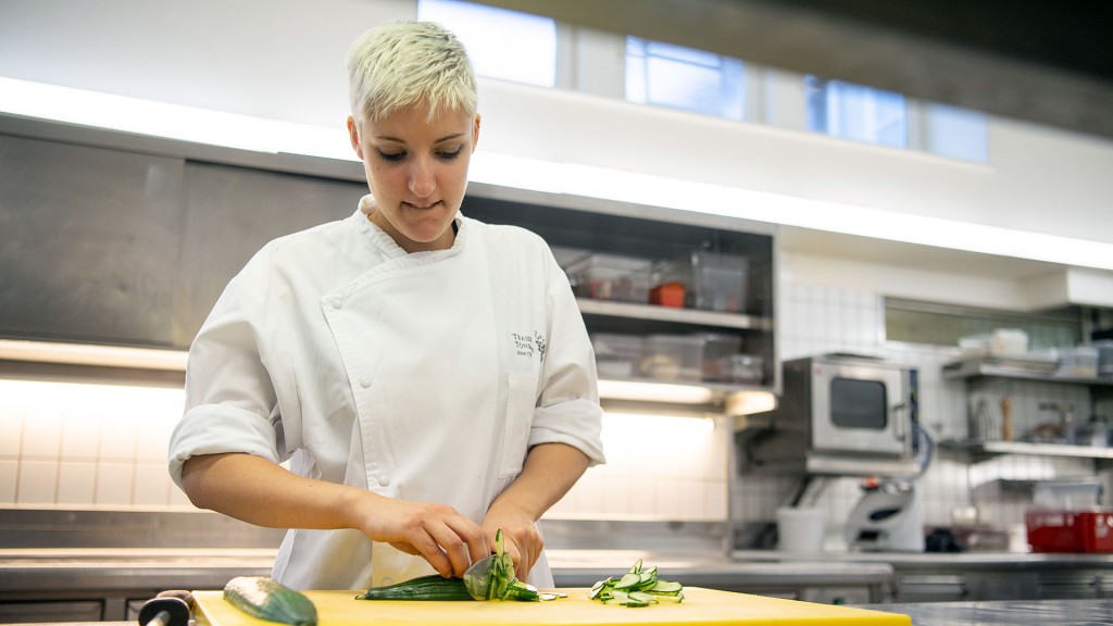 Foto: Eine auszubildende Köchin schneidet Gemüse in einer Restaurantküche