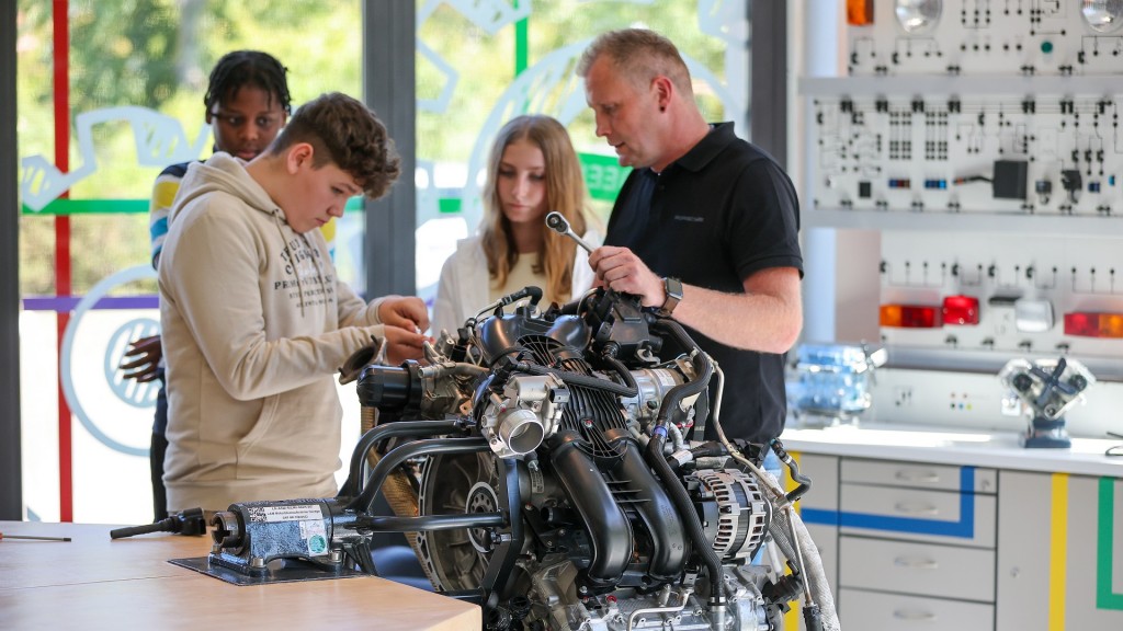 Ein Ausbilder erläutert den Wechsel der Zündkerzen an einem Motor.