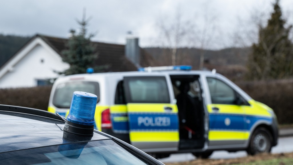 Foto: Einsatzfahrzeuge der Polizei stehen mit Blaulicht bei einem Wohngebiet.