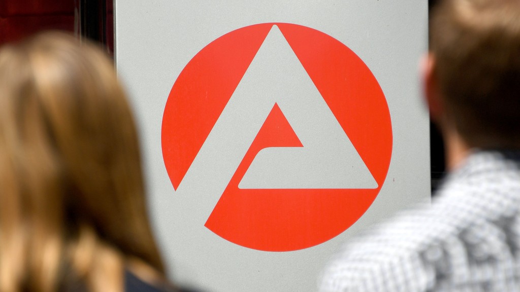 Zwei Personen stehen vor dem Logo der Agentur für Arbeit