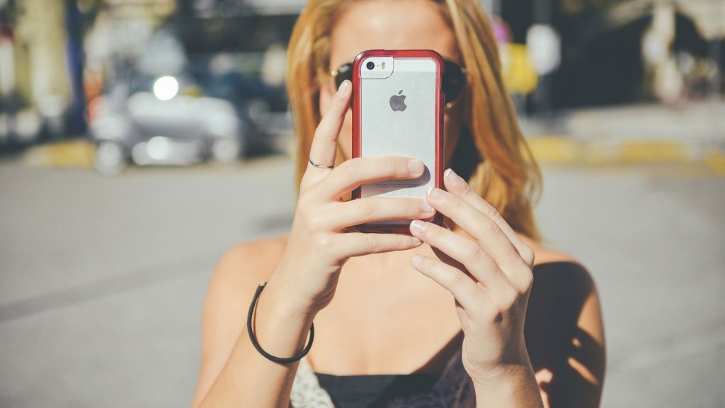 Eine Frau verdeckt mit dem Smartphone ihr Gesicht
