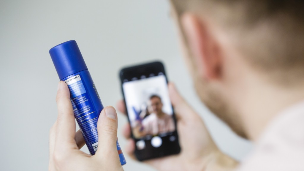 Ein Mann hält eine Sprayflasche und ein Smartphone in den Händen