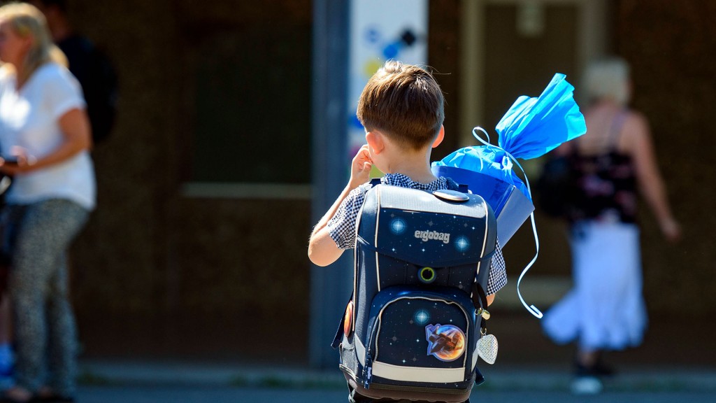 Foto: Ein Junge läuft mit Schultüte und -ranzen über den Hof