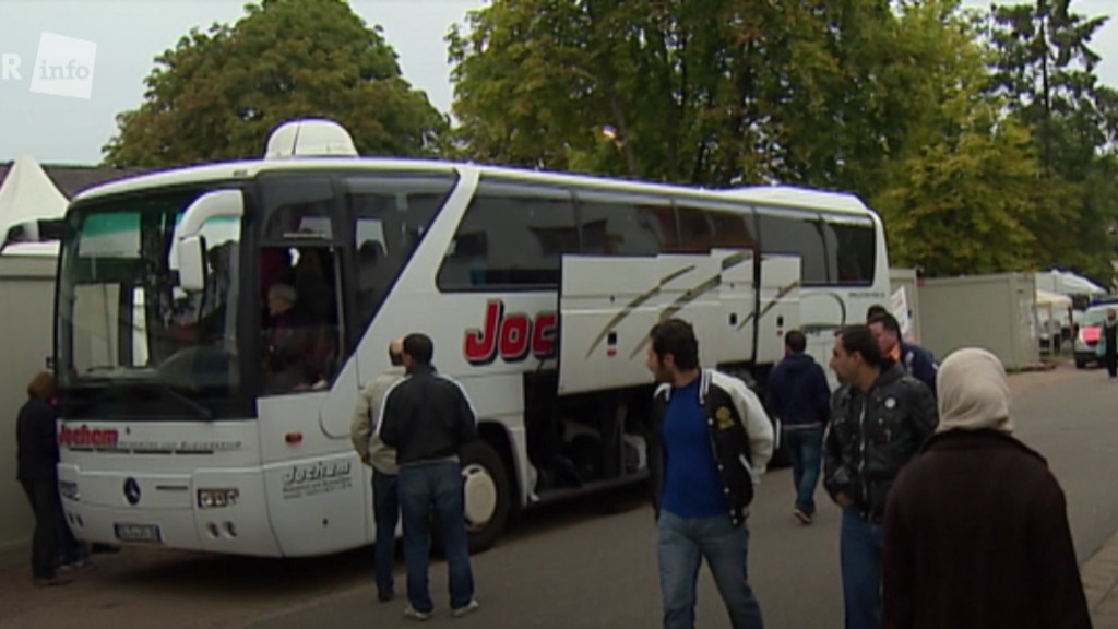 Foto: Syrische Geflüchtete bei ihrer Ankunft in Deutschland 2015 vor einem Reisebus