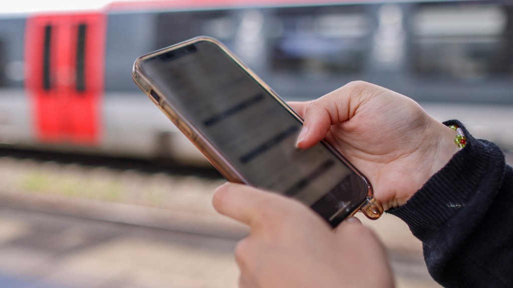 Frau mit iPhone in der Hand. Im Hintergrund eine Bahn.