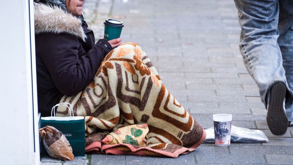 Eine Person sitzt bei kalten Temperaturen bettelnd am Gehwegrand