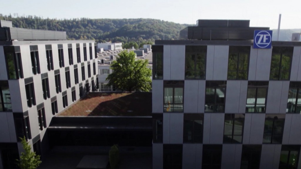 Unscharf ist das Logo des Getriebeherstellers ZF im Hintergrund durch eine Baumkrone zu erkennen