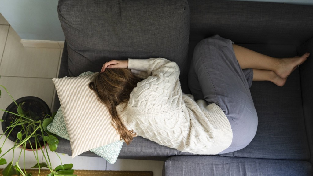 Foto: Junge Frau liegt gekrümmt auf dem Sofa