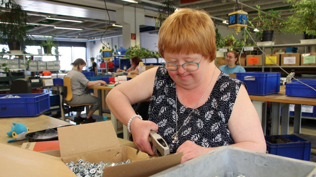 Ein junge Frau mit Behinderung verpackt und sortiert Schrauben in den Bübinger Werken in Saarbrücken.
