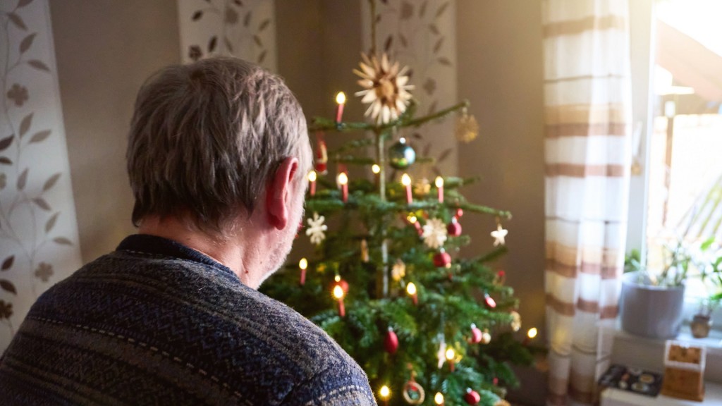 Mann betrachtet Weihnachtsbaum.