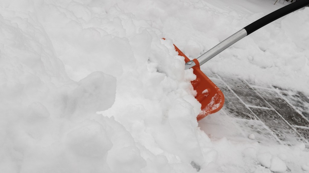 Ein Gehweg wird mithilfe einer Schneeschaufel geräumt