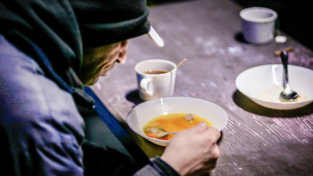 Foto: Ein Obdachloser sitzt in einer Kältehilfe-Einrichtung beim Essen