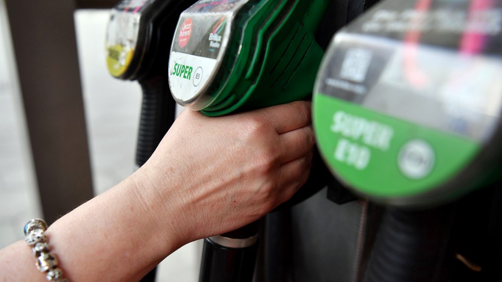 Foto: Eine Hand greift nach einer Zapfpistole an der Tankstelle