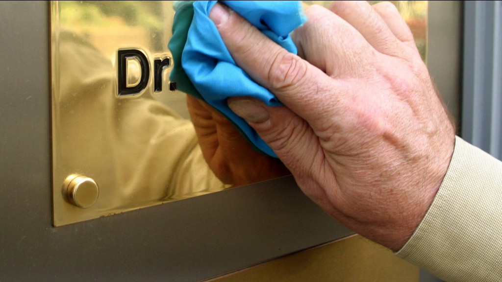 Eine Hand poliert das glänzende Messingschild mit der Beschriftung 