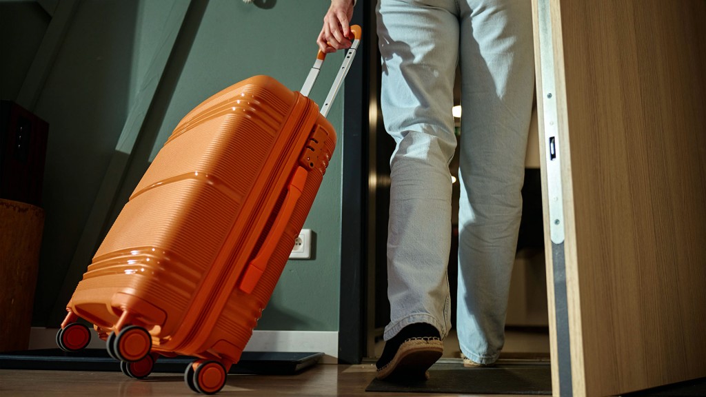 Jemand verlässt eine Wohnung mit einem Reisekoffer