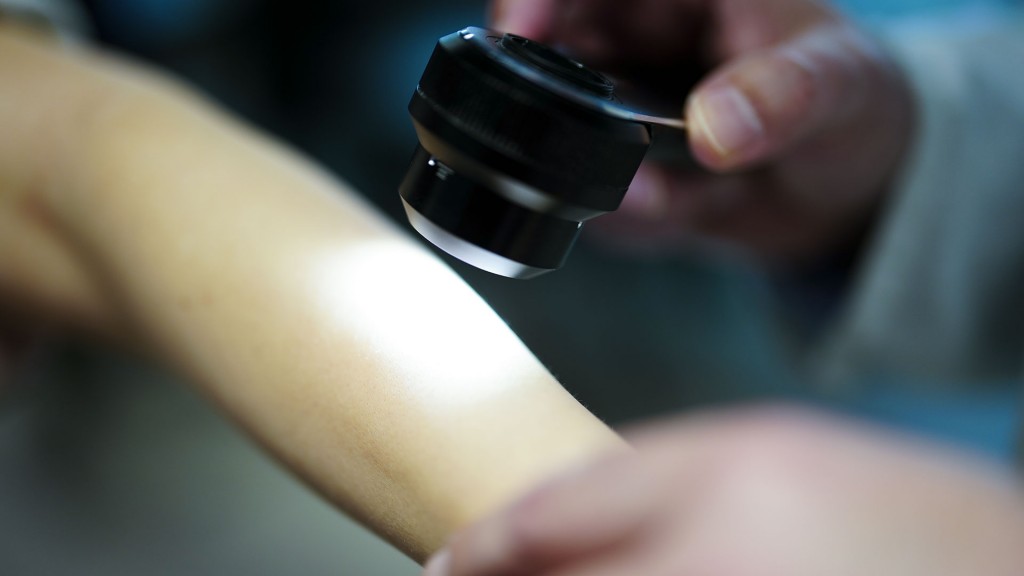 Ein Hautarzt untersucht bei einer Krebsvorsorgeuntersuchung eine Patientin mit einem Auflichtmikroskop.