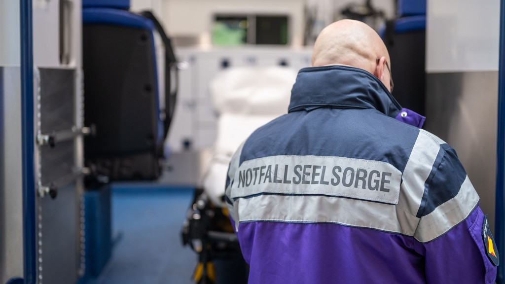 Notfallseelsorger vor offenem Rettungswagen.