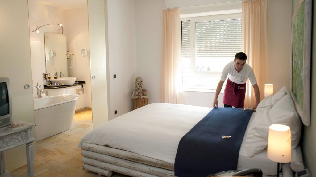 Ein Servicemitarbeiter richtet das Bett in einem Hotelzimmer