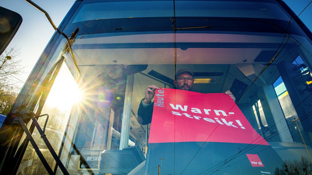 Ein Streik-Plakat der Gewerkschaft Verdi wird in die Frontscheibe eines Linienbusses gehängt