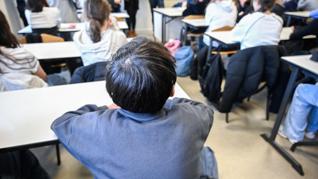 Schüler einer 5. Klasse sitzen in den Bänken eines vollen Klassenraums.