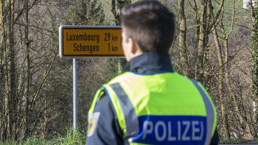 Grenzkontrolle. Ein Polizist steht auf deutscher Seite an der Grenze vor dem Wegweiser nach Luxemburg