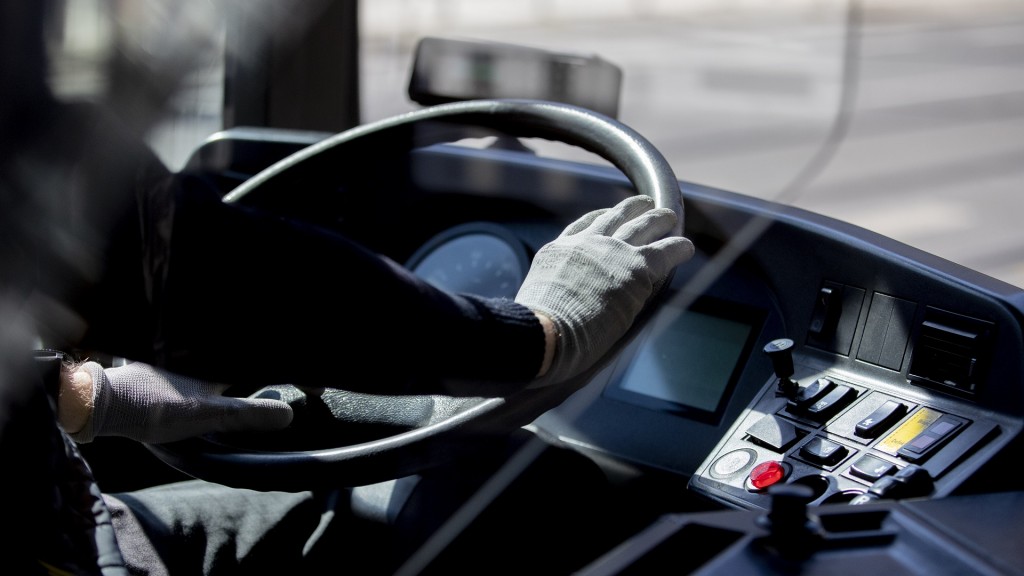 Ein Busfahrer hält das Lenkrad mit Handschuhen. 