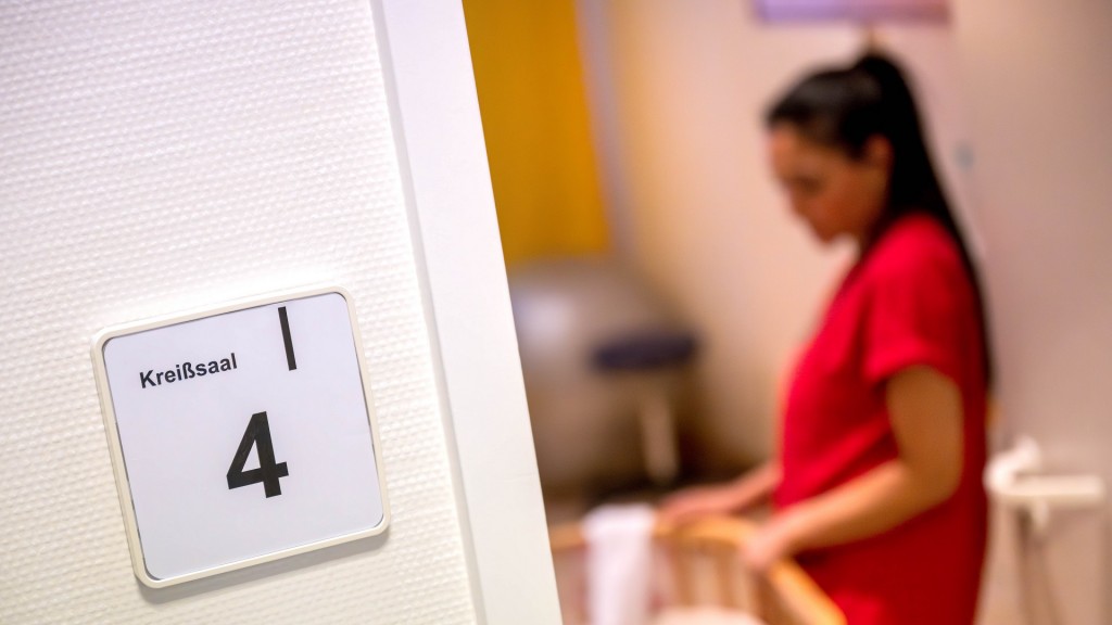 Eine Hebamme steht an einem Bett im Kreißsaal.