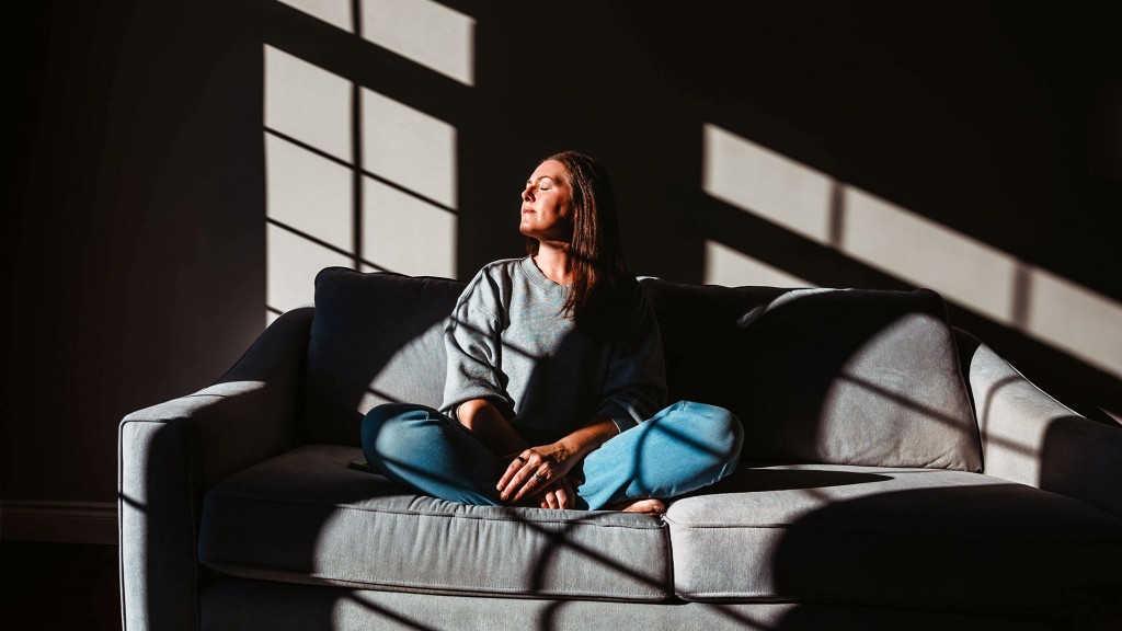 Eine Frau sitzt im Sonnenlicht eines großen Fensters auf einer Couch