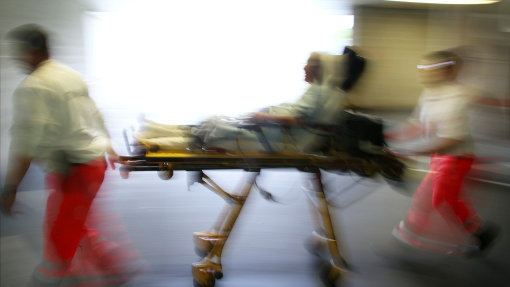 Rettungsassistenten liefern eine Notfallpatientin auf einer Trage in ein Krankenhaus ein