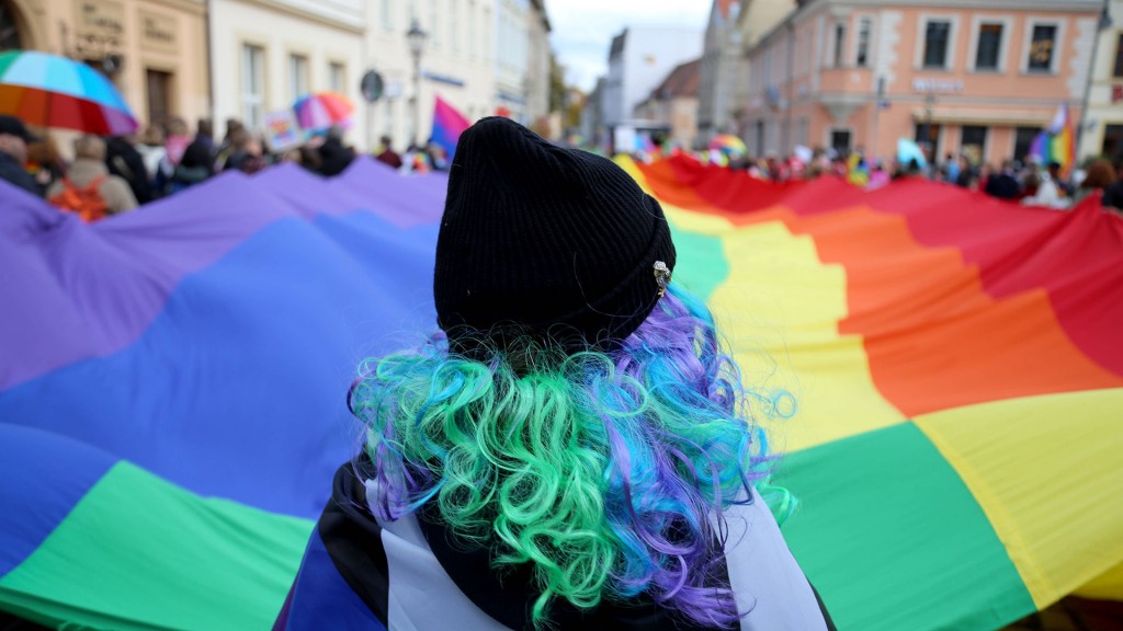 Frau mit bunten Haaren vor Regenbogenflagge