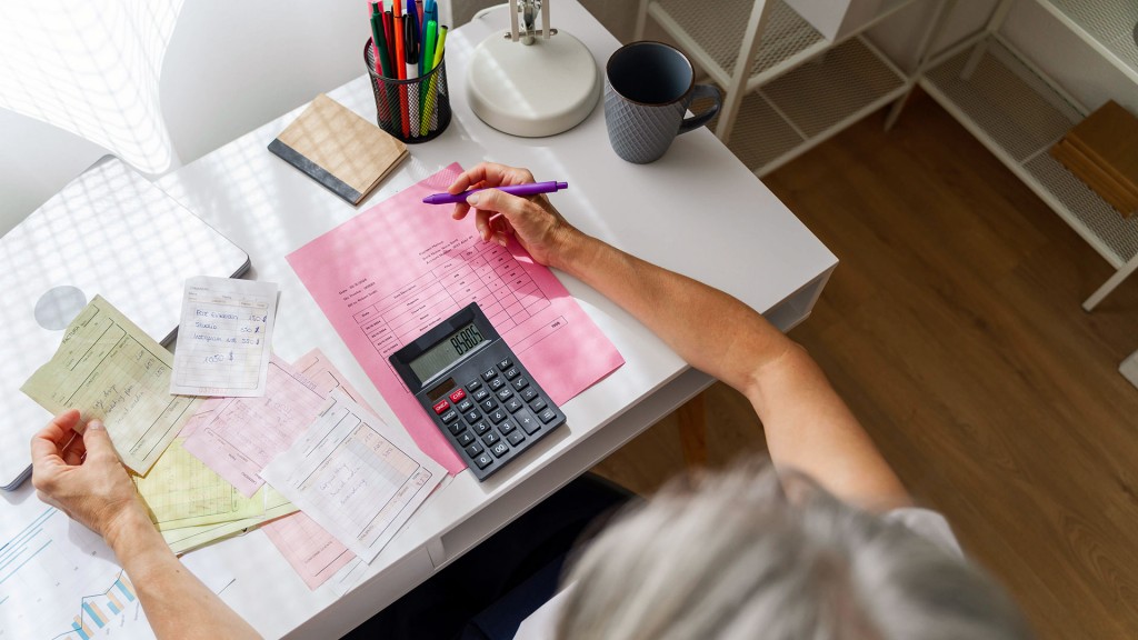 Eine Frau sitzt am Schreibtisch mit Unterlagen und Rechner