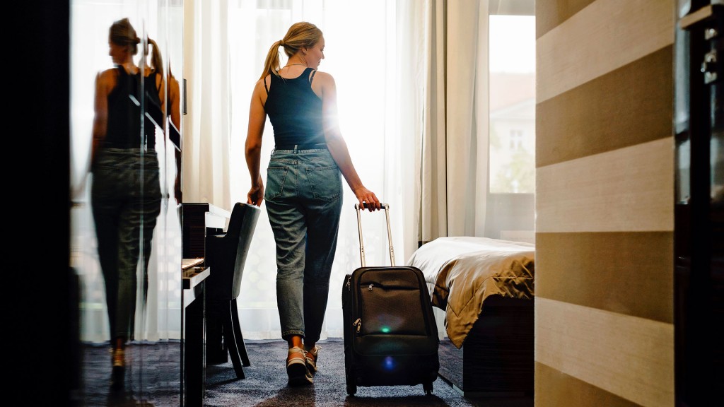 Ein Frau betritt ein Hotelzimmer mit ihrem Gepäck