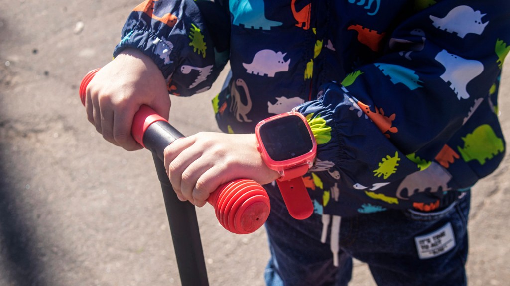 Foto: Nahaufnahme einer Kinderhand mit einer Smartwatch, die den Lenker eines Rollers hält.