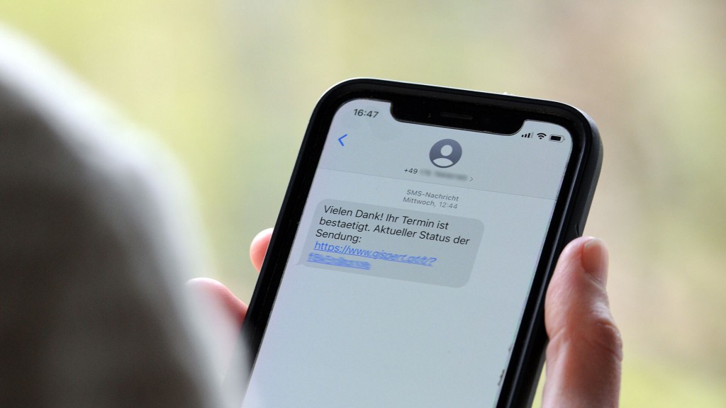 Eine Frau hält ein Smartphone in ihrer Hand, auf dessen Display eine Betrugs-SMS zu lesen ist