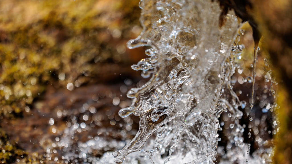 Foto: Makro-Nahaufnahme von kristallklarem Wasser, das über moosbewachsene Felsen spritzt