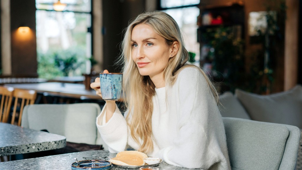 Eine Frau sitzt zufrieden alleine an einem Tisch im Café