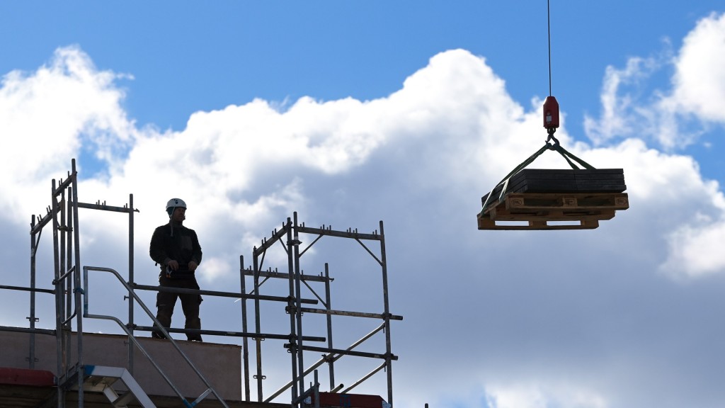 Ein Arbeiter dirigiert auf einer Baustelle einen Kran. 