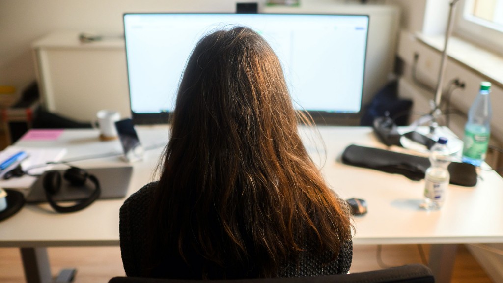 Eine Frau sitzt vor einem großen Bildschirm am Schreibtisch