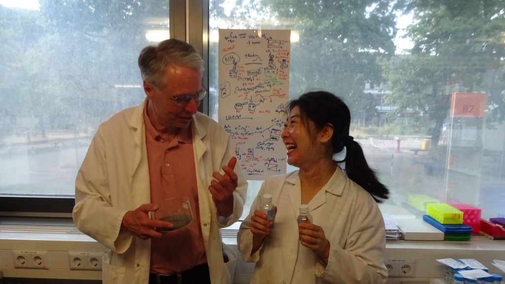 Prof. Claus Jacob hält ein Schälchen mit Holzasche in der Hand, Zhengyu Li kleine Fläschchen mit Kuhurin.