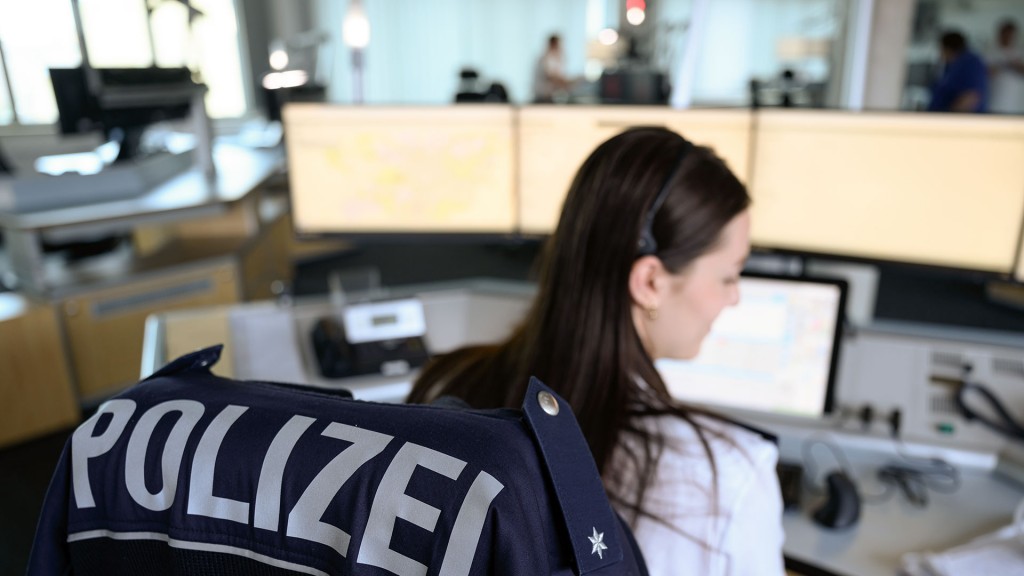 Foto: Eine Polizistin sitzt vor mehreren Computerbildschirmen