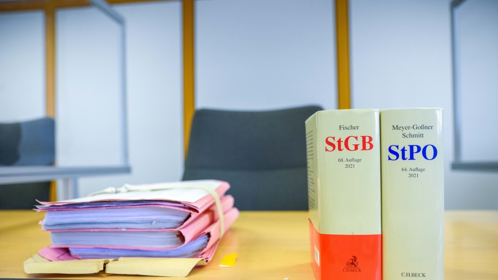 Foto: Akten, Strafgesetzbuch und eine Strafprozessordnung auf dem Tisch im Gerichtssaal